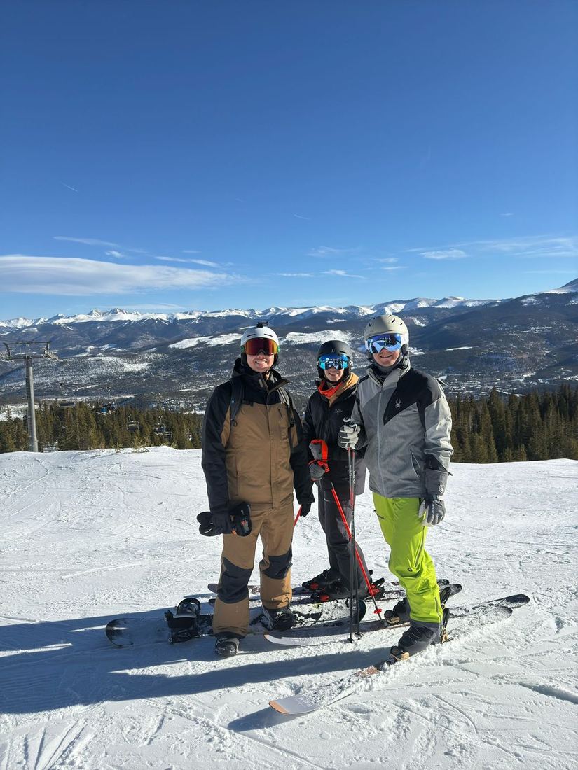 Gabe and his two brothers on skis and a snowboard at the top of a run in Breckenridge.
